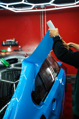 Wet PPF Wrapping on Car Panel in detailing center. Protective film layering during PPF wrap detailing to protect the car surface from scratches and UVの写真素材