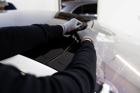 Auto technician separates windshield using fine wire and scraping blade. Car windshield replacement...