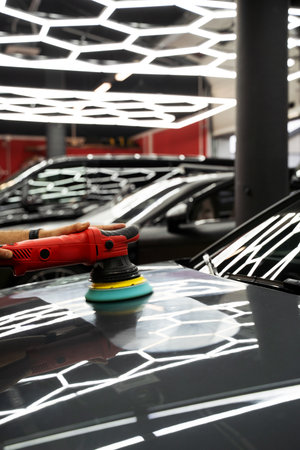 Car paint correction and polishing. Polishing machine expertly removes paint swirls and oxidation for a flawless surface. Polishing revives vehicle paint with deep gloss and smoothnessの写真素材