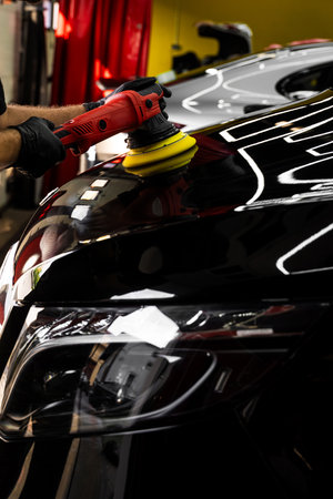 Car hood being polished with yellow pad. Paint polishing in active motion. Paint polishing to eliminate swirl marks and restore deep gloss. Detailing car for sealant or ceramic applicationの写真素材