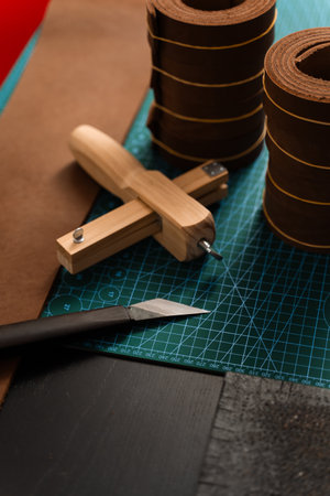Leather rolls and strap cutter lie on cutting mat, ready for trimming strong belts and leather...