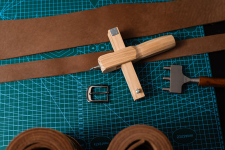 Leathercraft tools and belt-making preparation. Leatherworking setup featuring tools, buckle, and...