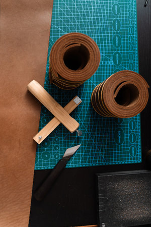 Leather rolls and strap cutter lie on cutting mat, ready for trimming strong belts and leather...