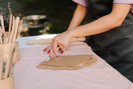 Ceramic artist cuts designs into clay with steady precision. Pottery Cutting Clay Close-up. Cutting...
