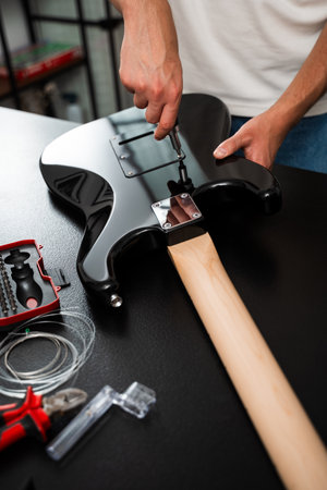 Electric Guitar Repair Backplate Using Screwdriver. Electric guitar repair highlights a technician...