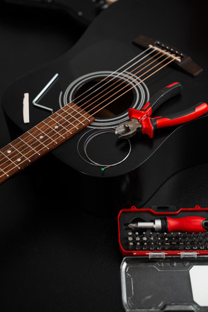 Restringing process with pliers and screwdriver kit near acoustic guitar. Guitar string replacement...