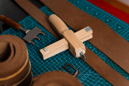 Leatherworking setup featuring tools, buckle, and leather strips laid out neatly on a mat, ready for...