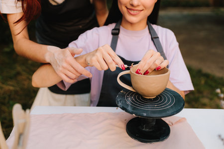 Process of sculpting clay bowls blends precision with creativity, highlighting craftsmanship and ceramic traditions. Pottery carving close-up. Artistry of carving clay pottery is shown in detailの写真素材