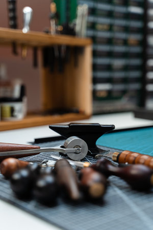 Leathercraft Tools on Workbench. Traditional wooden-handled awls and cutters beside a small anvil...