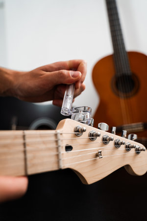 Guitar Maintenance and String Replacement. Guitar headstock being adjusted with a string winder....