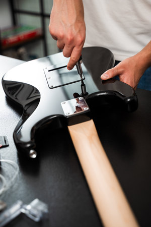 Electric guitar repair highlights a technician tightening the backplate screws with accuracy. Electric Guitar Repair Backplate Using Screwdriverの写真素材