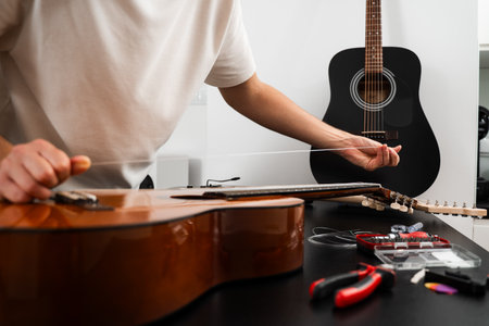 Installing new guitar strings. Musician installing a new string on an acoustic guitar. Acoustic...