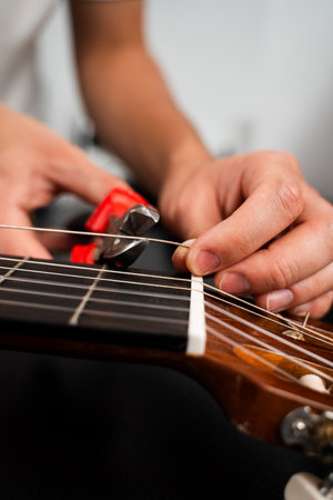 Guitarist trims new strings with pliers during a classical guitar restringing process. Cutting Guitar Strings with Pliers. Classical guitar string replacement and trimmingの写真素材