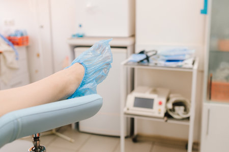 Girl awaits consultation in a gynecological office with specialized tools. Woman seated in gynecology chair before examination. Modern gynecological chair and microscope ready for gynecology examの写真素材