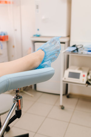 Woman seated in gynecology chair before examination. Modern gynecological chair and microscope ready for gynecology exam. Girl awaits consultation in a gynecological office with specialized toolsの写真素材