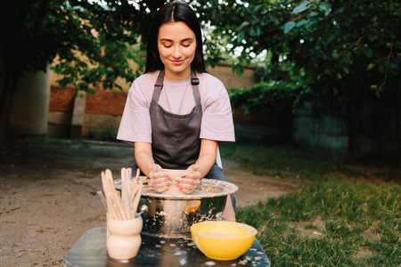 Girl shapes clay with smile. Smiling artisan shapes clay. Young woman smiling while working with clayの写真素材