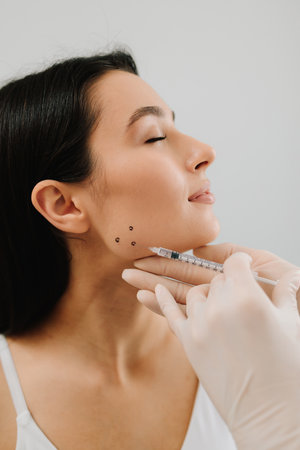 Bruxism injection facial for a treatment with botulinum toxin in an aesthetic medicine clinic. Bruxism injecting for teeth grinding by a cosmetologistの写真素材