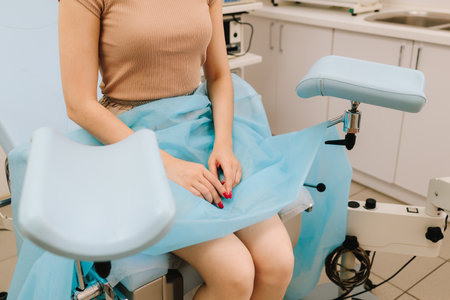 Modern gynecological chair and microscope ready for gynecology exam. Girl awaits consultation in a gynecological office with specialized tools. Woman seated in gynecology chair before examinationの写真素材