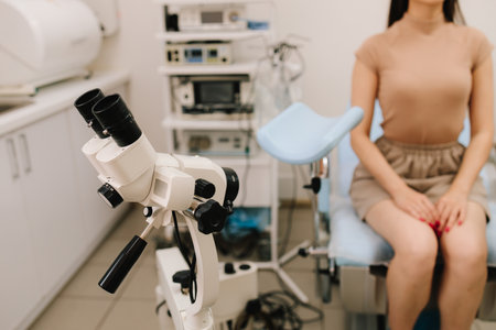 Girl awaits consultation in a gynecological office with specialized tools. Woman seated in gynecology chair before examination. Modern gynecological chair and microscope ready for gynecology examの写真素材