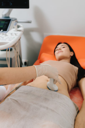 Gynecologist uses ultrasound equipment for reproductive health evaluation. Gynecologist performs an abdominal ultrasound on a relaxed patient. Abdominal ultrasoundの写真素材