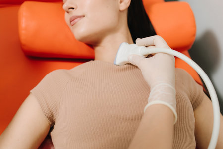 Girl undergoes an ultrasound test as the probe captures internal structures. Ultrasound Procedure with Patient. Doctor performs an ultrasound examination on the patient using a handheld probeの写真素材
