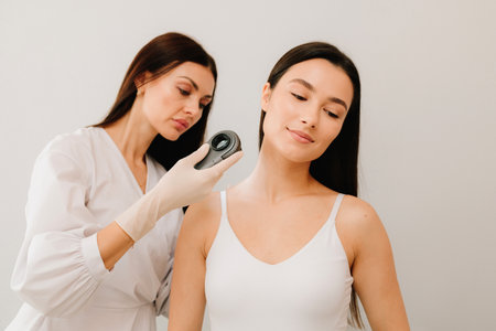 Dermatologist Examining Girl Skin with Dermatoscope. Dermatoscopic analysis aids in the detection of suspicious skin spots using dermatoscope during a clinical examの写真素材