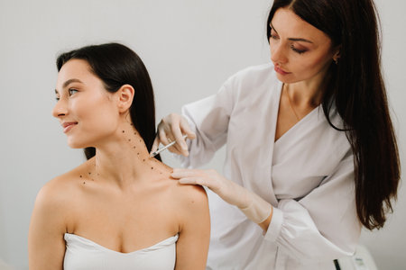 Cosmetologist is drawing dotes before botulinum toxin injection in platysma of girl. Nefertiti...