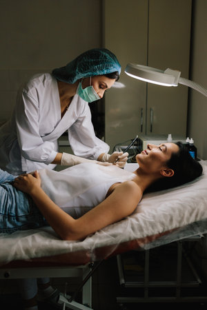 Dermatologist performs precise radio wave mole removal using radiofrequency surgery. Close-up of radio wave dermatologic mole excision. Radiofrequency mole removal under clinical conditionsの写真素材