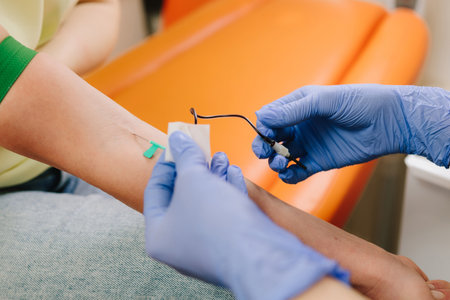 Insert a needle for blood collection close-up. Nurse in sterile gloves performs a venipuncture, collecting blood for diagnostic testing in a controlled clinical environmentの写真素材