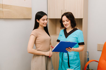 Consultation between a gynecologist and patient involves reviewing health data to ensure preventive reproductive care. Gynecologist Consultation with Medical Recordsの写真素材