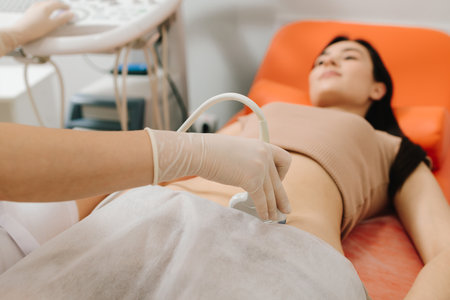 Abdominal ultrasound. Gynecologist uses ultrasound equipment for reproductive health evaluation. Gynecologist performs an abdominal ultrasound on a relaxed patientの写真素材