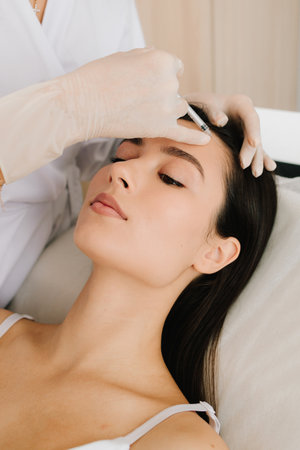 Forehead Injection close-up. Forehead botulinum toxin injection smooths fine lines and relaxes muscles. Non-surgical forehead rejuvenation with botulinum toxinの写真素材