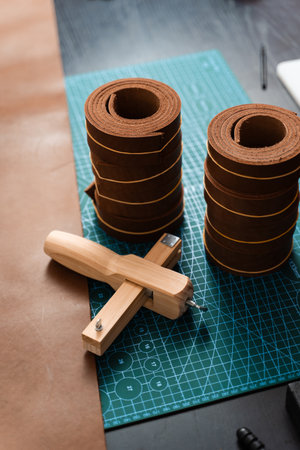 Sharp strap cutter and leather rolls, essential for crafting accurate belt straps. Leather rolls and strap cutter lie on cutting mat, ready for trimming strong belts and leather goodsの写真素材