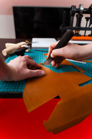 Cutting leather with knife. Craftsman carefully cuts leather with precision tools. Craftsman...