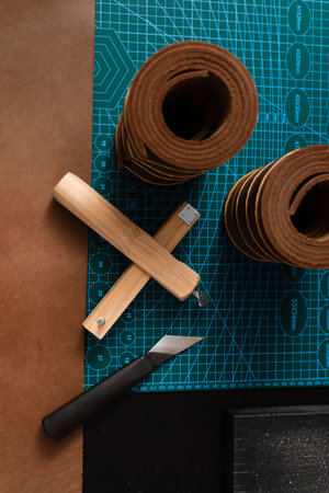 Sharp strap cutter and leather rolls, essential for crafting accurate belt straps. Leather rolls and strap cutter lie on cutting mat, ready for trimming strong belts and leather goodsの写真素材