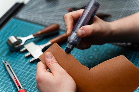 Edge finishing with dye marker. Artisan applies edge dye to leather piece, enhancing durability....