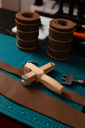 Leatherworking setup featuring tools, buckle, and leather strips laid out neatly on a mat, ready for belt making. Leathercraft tools and belt-making preparationの写真素材