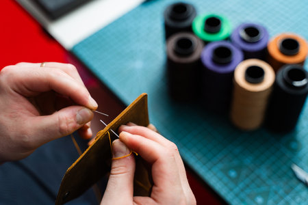 Hand Stitching Leather with Waxed Thread. Hand stitching leather with waxed thread creates durable seams. Leather artisans use needles and waxed thread to craft strong seamsの写真素材
