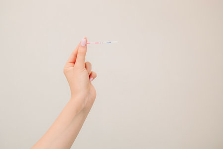 Future mother holds positive pregnancy test with positive result on white backgroundの写真素材