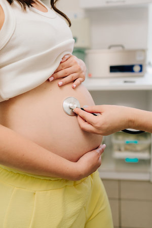 Gynecologist with stethoscope listening baby heartbeat in patient tummy on the appointment in gynecology clinic. Pregnancy checkupの写真素材