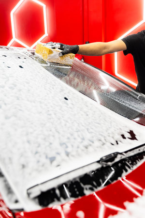 Hand car wash detailing sponge stage removes dirt and debris, leaving the car paint smooth and glossy. Sponge washing to clean every panel without scratching or damaging the paintの写真素材