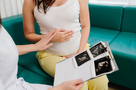 Consulting patient about high hemoglobin and blood pressure during pregnancy on the gynecologist appointment. Gynecologist discusses the results of blood test of a pregnant womanの写真素材
