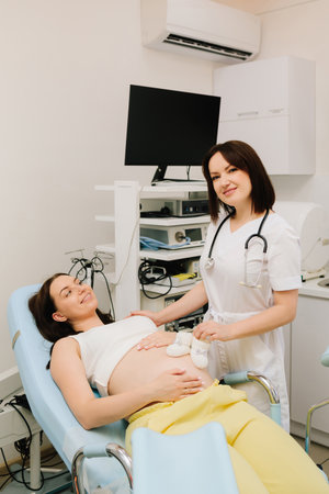 Expecting mother with tiny baby booties while waiting for her baby. Pregnant woman and gynecologist...