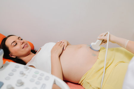 Pregnant woman on ultrasound examination at hospital. Pregnancy health checkup with ultrasound equipmentの写真素材