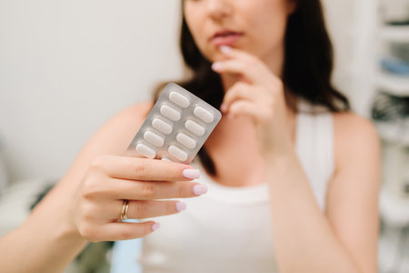 Medical pills for healthy pregnancy. Pregnant woman takes vitamin pills with water at homeの写真素材
