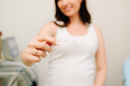 Happy future mother holds positive pregnancy test with positive result in gynecology clinicの写真素材