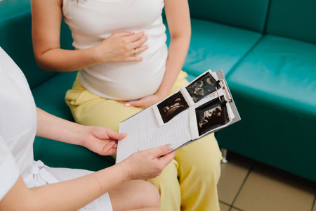 Gynecologist discusses the results of blood test of a pregnant woman. Consulting patient about high hemoglobin and blood pressure during pregnancy on the gynecologist appointmentの写真素材