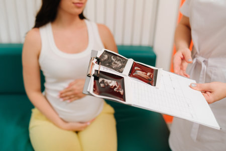 Gynecologist discusses the results of blood test of a pregnant woman. Consulting patient about high hemoglobin and blood pressure during pregnancy on the gynecologist appointmentの写真素材