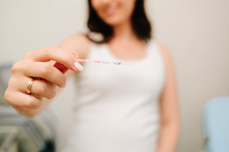 Happy future mother holds positive pregnancy test with positive result in gynecology clinicの写真素材