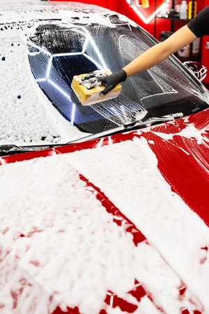 Sponge washing to clean every panel without scratching or damaging the paint. Hand car wash detailing sponge stage removes dirt and debris, leaving the car paint smooth and glossyの写真素材